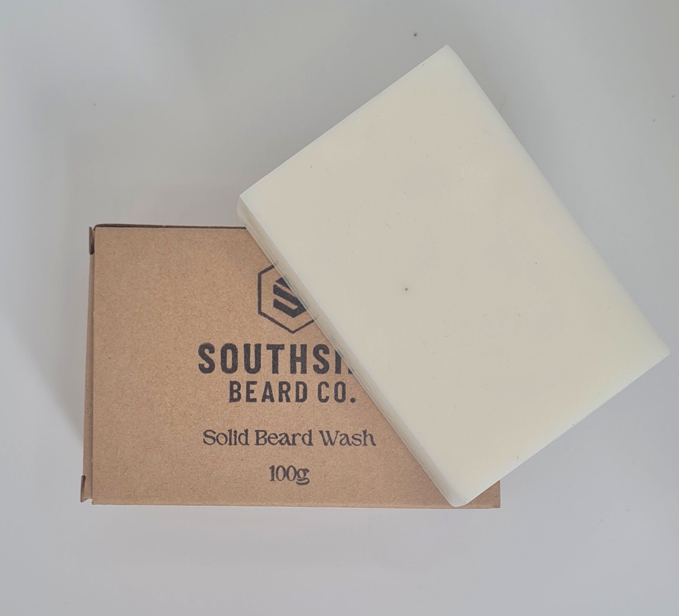 unscented solid beard shampoo from southside beard co on a white background. Beard shampoo resting on packaging with the logo showing from a birds eye view.