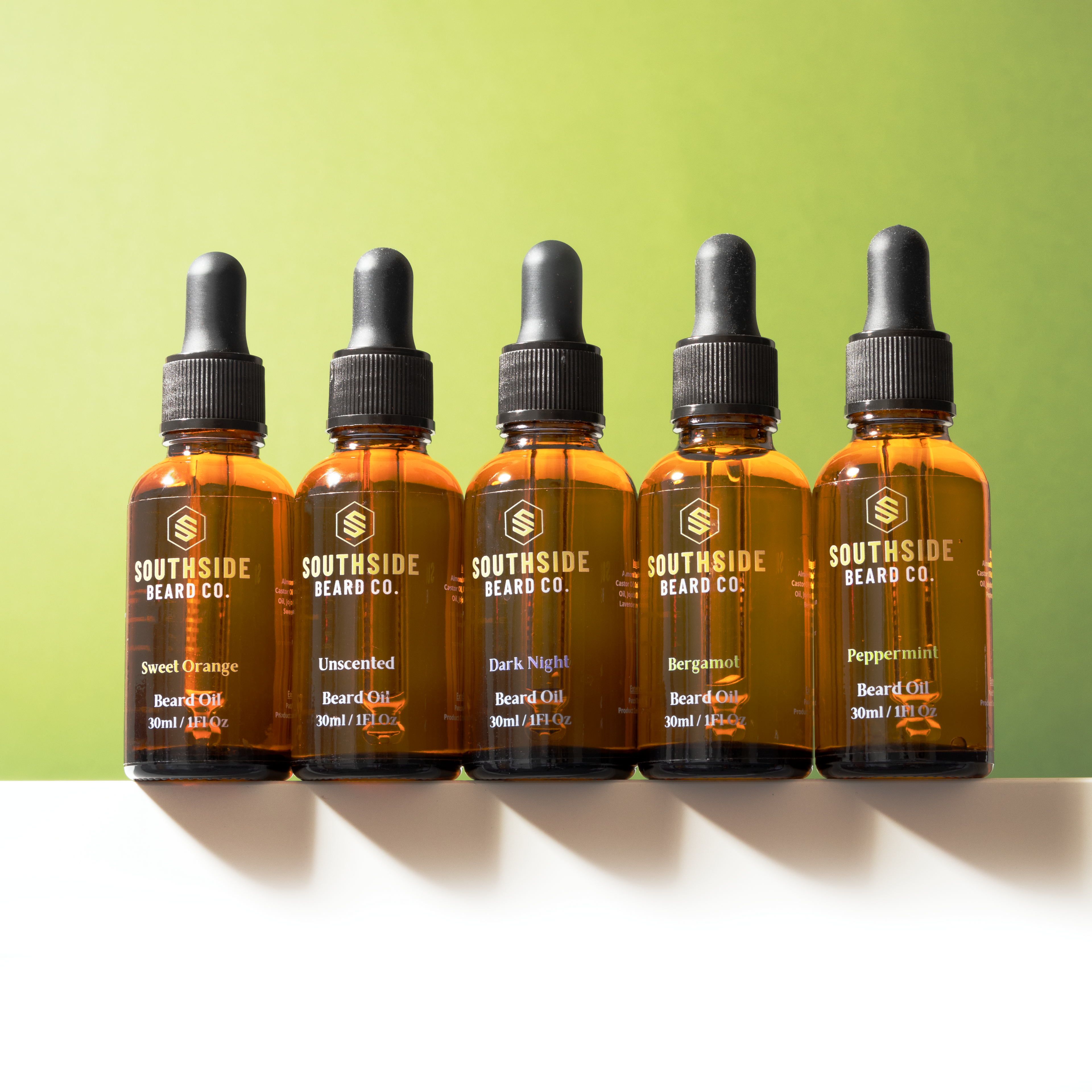Five bottles of Southside Beard Co. beard oil on a white surface with a green background