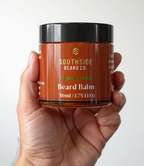 Hand holding a Southside Beards Co. peppermint beard balm jar against a white background