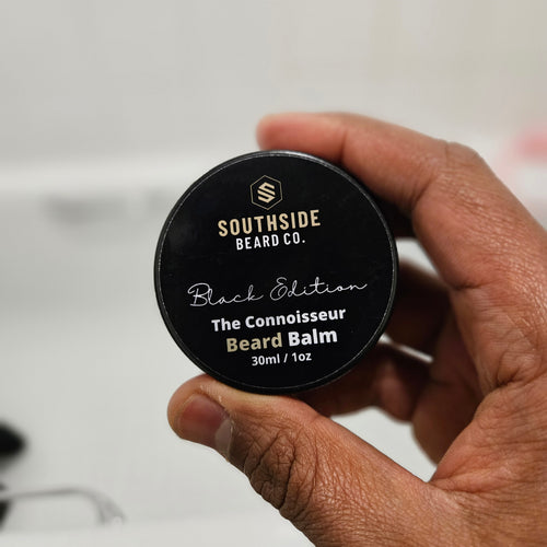 Hand holding a Southside Beard Co. The connoisseur beard balm container against a neutral background