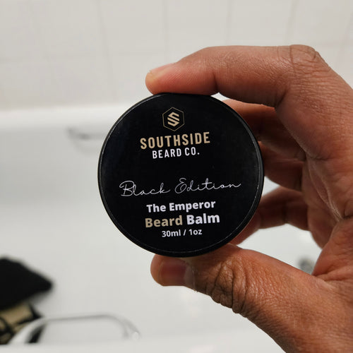 Hand holding a Southside Beard Co. The emperor beard balm container against a neutral background