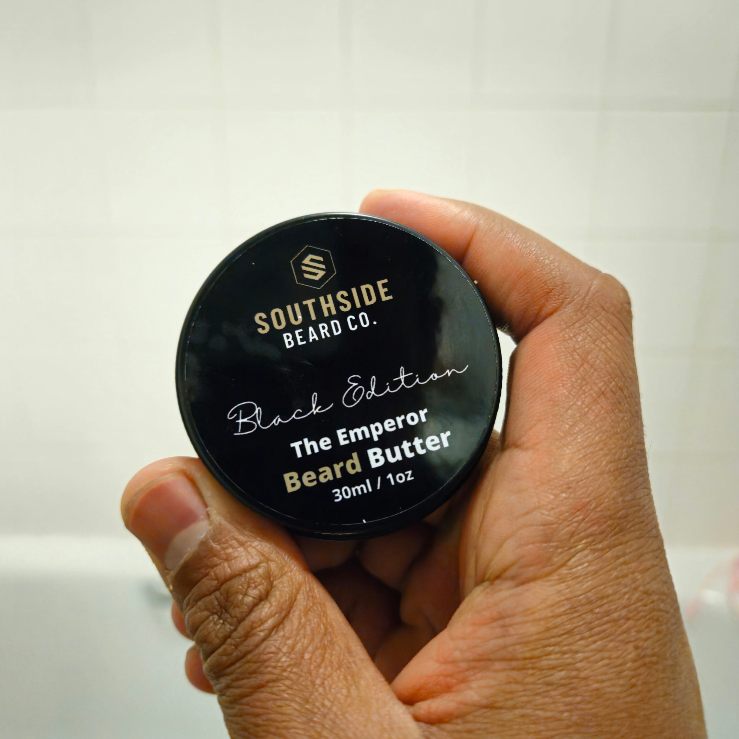 Hand holding a Southside Beard Co. Black Edition Emperor Beard Butter container.